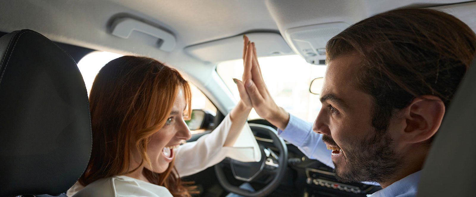 Young couple high-fiving after buying a new car