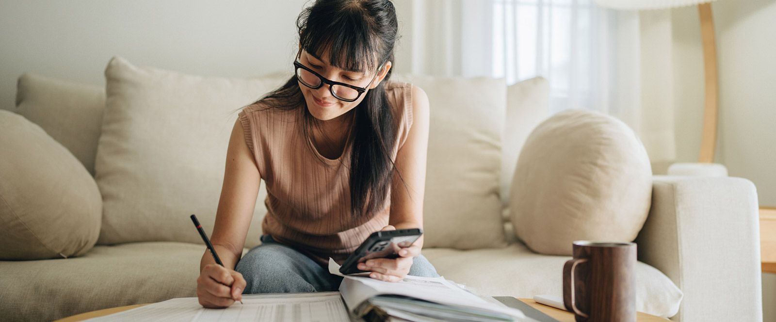 Woman using calculator and going over finances in living room